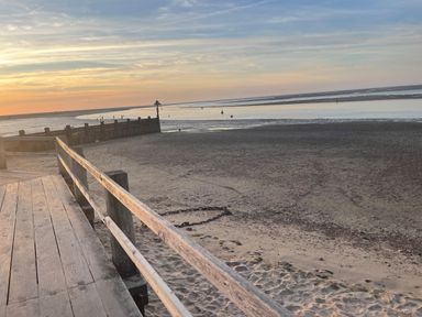 A wooden boardwalk with railings overlooking a sandy beach and calm sea at Jolly Sailors Retreat - Wells next the Sea in Wells-Next-The-Sea