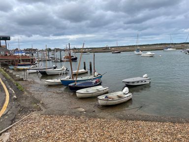 A harbor with small boats docked by the shore under a cloudy sky at Jolly Sailors Retreat - Wells next the Sea in Wells-Next-The-Sea