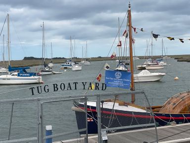 A harbor with moored sailboats and yachts behind a gate labeled Tug Boat Yard at Jolly Sailors Retreat - Wells next the Sea in Wells-Next-The-Sea
