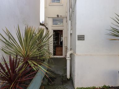 A narrow entrance with plants along the left side and a door at the end at Mimosa Cottage in Dawlish