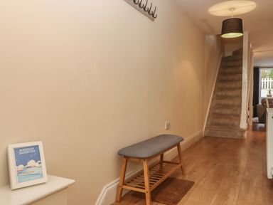 A hallway with a wooden bench and carpeted stairs at Mimosa in Dawlish