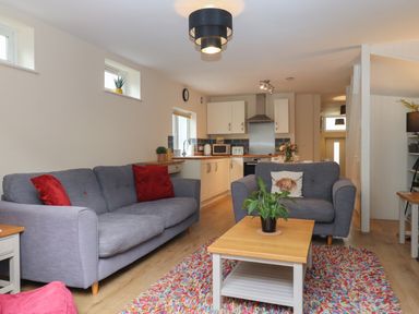 A living room with grey sofas red cushions and a wooden coffee table with a plant at Mimosa in Dawlish