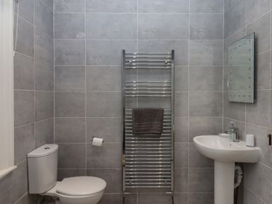 A bathroom with a toilet pedestal sink towel rail and mirror at Mimosa in Dawlish