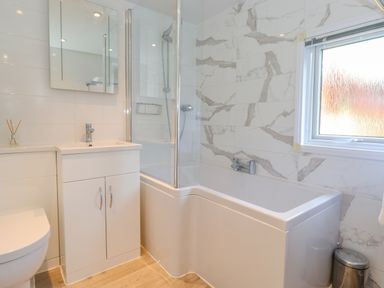 A bathroom with a bathtub shower combination sink with cabinet mirror and window at Fell Foot Lodge Fellside 9 Limefitt Park near Troutbeck