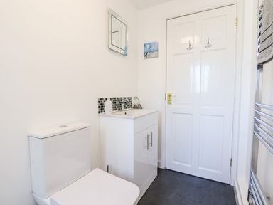 A bathroom with a toilet sink vanity mirror and a door at Little Rowan at Rowan Park Farm in Ashwater