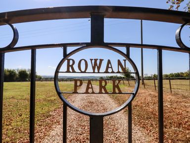 A metal gate with the words rowan park and a gravel driveway at Little Rowan at Rowan Park Farm in Ashwater