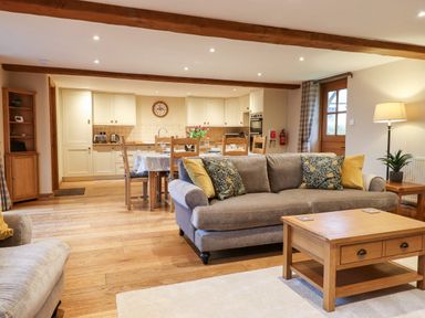 An open living area with a sofa coffee table dining table and kitchen at Little Orchard in Ashburton Down near Ashburton