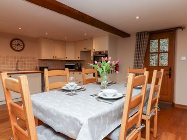A kitchen with a dining table set with dishes and a vase of flowers at Little Orchard in Ashburton Down near Ashburton