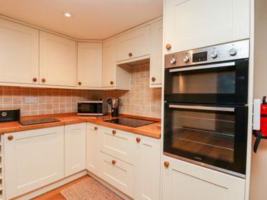 A kitchen with built in oven microwave stovetop wooden cabinets and a fire extinguisher at Little Orchard in Ashburton Down near Ashburton