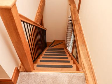 A wooden staircase with black grip strips and a black metal railing at Little Orchard in Ashburton Down near Ashburton