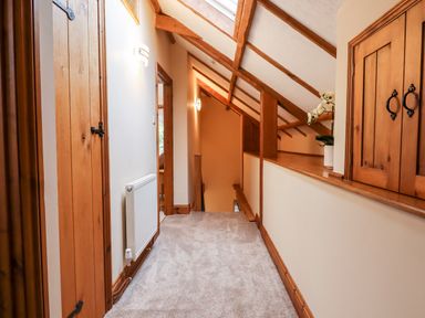 A carpeted upstairs hallway with wooden doors and exposed wooden beams at Little Orchard in Ashburton Down near Ashburton