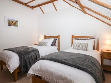 A bedroom with two single beds wooden headboards bedside tables and lamps at Little Orchard in Ashburton Down near Ashburton