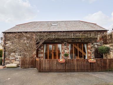 Stone cottage with wooden fence and two flower pots at Little Orchard in Ashburton Down near Ashburton