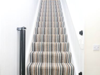 A staircase with striped carpet at The Abbey Grange near Charmouth