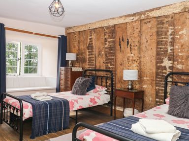 A bedroom with two beds and a wooden wall at The Abbey Grange near Charmouth