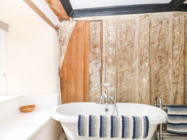 A bathroom with a bathtub and wooden walls at The Abbey Grange near Charmouth