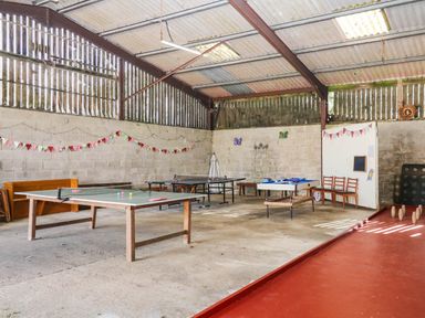 A recreation room with tables and ping pong table at The Abbey Grange near Charmouth