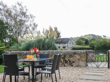 A table with drinks and chairs in a garden at The Abbey Grange near Charmouth