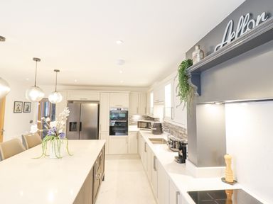 A kitchen with an island countertop floral arrangement pendant lights and modern appliances at Aelfor in Harlech