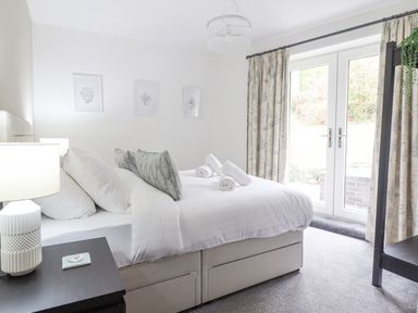 A bedroom with a double bed with white bedding pillows and rolled towels and bedside table with lamp at Aelfor in Harlech