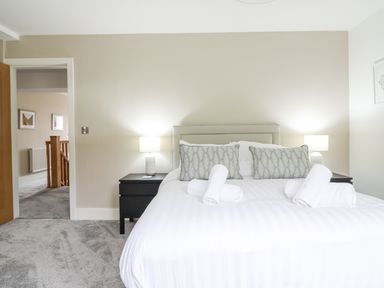 A bedroom with a double bed with rolled towels pillows bedside tables and lamps at Aelfor in Harlech