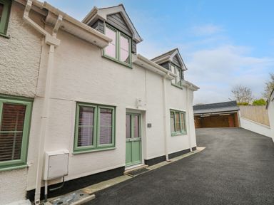 A street view of a white house with green window frames and a green door at 2 Penporth in Rhayader