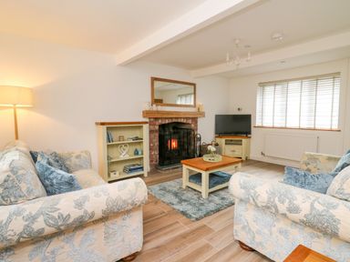 A living room with floral sofas a fireplace wooden coffee table and television at 2 Penporth in Rhayader