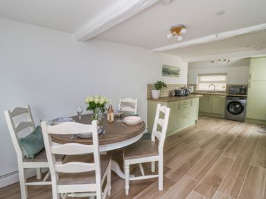 A kitchen and dining area with a round wooden table set for four and green cabinets at 2 Penporth in Rhayader