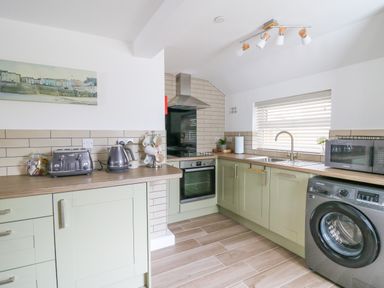 A kitchen with appliances including oven kettle toaster microwave washing machine and cabinets at 2 Penporth in Rhayader