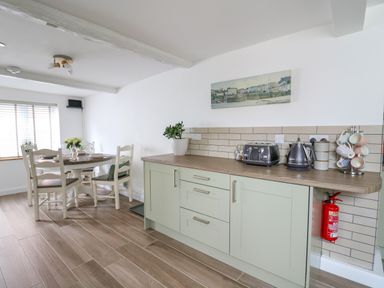 A kitchen and dining area with light green cabinets a round table and chairs at 2 Penporth in Rhayader