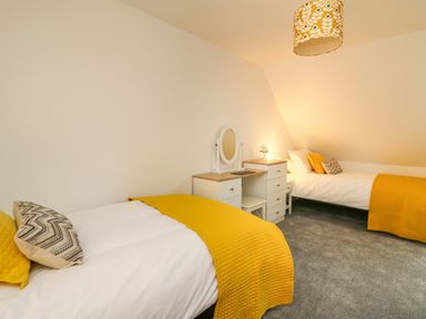 A bedroom with two single beds a vanity table and chair and gray carpet at 2 Penporth in Rhayader