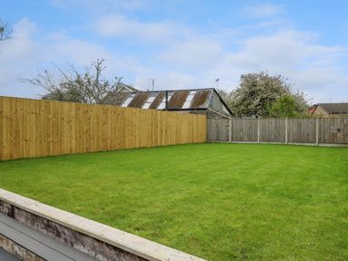 A backyard with green grass and wooden fences at 2 Penporth in Rhayader
