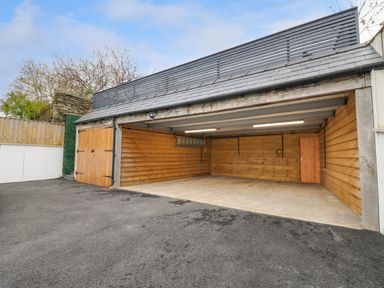 An empty double garage with wooden walls and concrete floor at 2 Penporth in Rhayader
