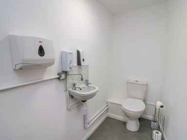 A small bathroom with a toilet sink wall-mounted soap and paper towel dispensers at 2 Penporth in Rhayader