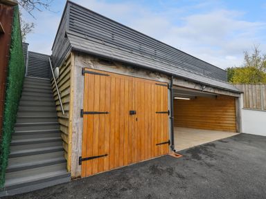 A garage with wooden doors and a stairway on the side at 2 Penporth in Rhayader