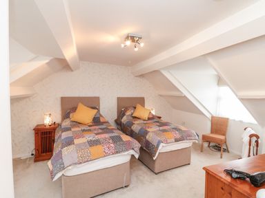 A bedroom with two single beds covered in patchwork quilts and a wooden side table with a lamp at Bluebell Cottage in Flamborough