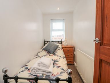 A small bedroom with a single bed and a wooden nightstand at Bluebell Cottage in Flamborough