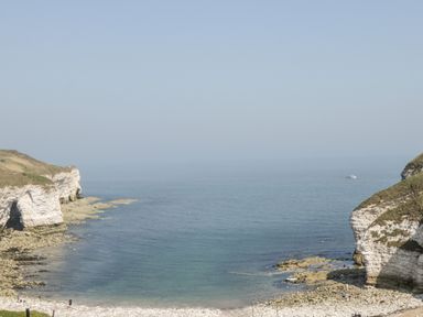A rocky shoreline with white cliffs and a small boat on the water at Bluebell Cottage in Flamborough