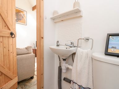 A small bathroom with a sink towel ring with towel and a framed picture on a toilet at Bluebell Cottage in Flamborough