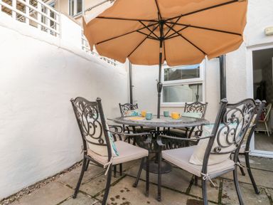 An outdoor patio with a round table set for four under an umbrella at Bluebell Cottage in Flamborough