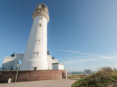A white lighthouse beside a brick wall and a road with a no exit sign at Bluebell Cottage in Flamborough