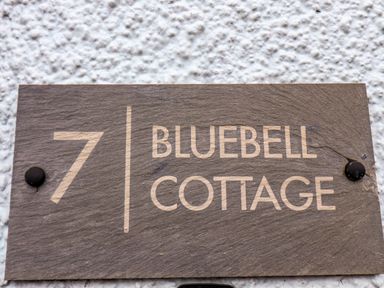 A house number 7 sign with Bluebell Cottage on a textured white wall at Bluebell Cottage in Flamborough