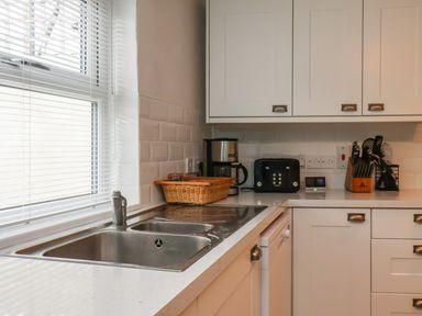 A kitchen counter with a sink coffee maker toaster knife block and utensils at Bluebell Cottage in Flamborough