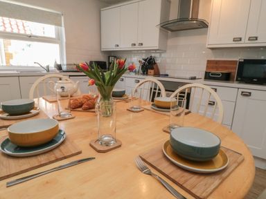 A dining table set with plates and glasses at Bluebell Cottage Flamborough