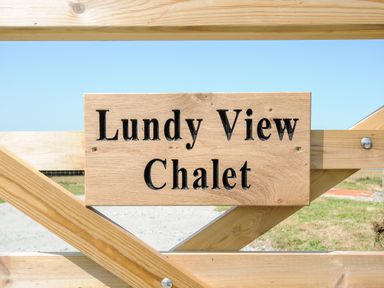 A wooden sign with the text Lundy View Chalet attached to a wooden fence in an outdoor area at Lundy View Chalet in Widemouth Bay