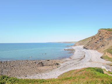 A rocky beach with cliffs and ocean at Lundy View Chalet in Widemouth Bay