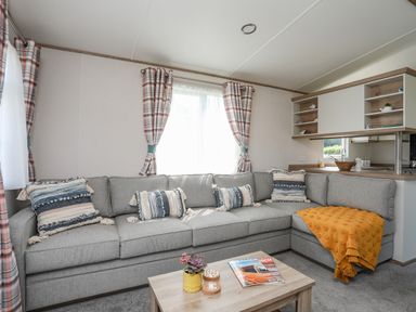 A living room with a grey corner sofa cushions and a wooden coffee table at Moondunes - Pwllheli in Chwilog
