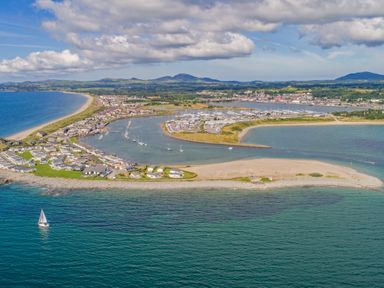 An aerial view of a coastal town with a marina beach houses and hills in the background at Moondunes - Pwllheli in Chwilog