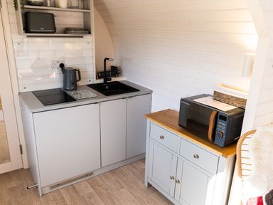 A small kitchen with a sink stove kettle toaster microwave and cabinet at Andrus - Mayflower Meadow in Brandesburton