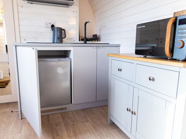 A kitchen area with a small fridge inside a cabinet a kettle on the countertop a microwave on a side cabinet at Andrus - Mayflower Meadow in Brandesburton